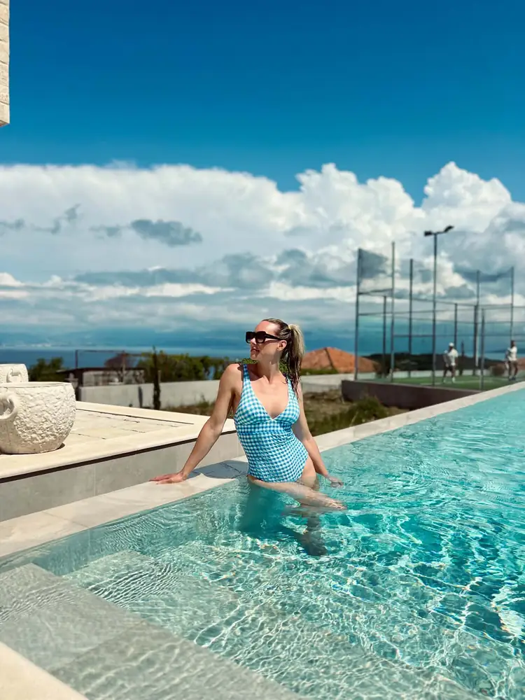 Frida ved kanten af infinity-poolen med padelbanen i baggrunden